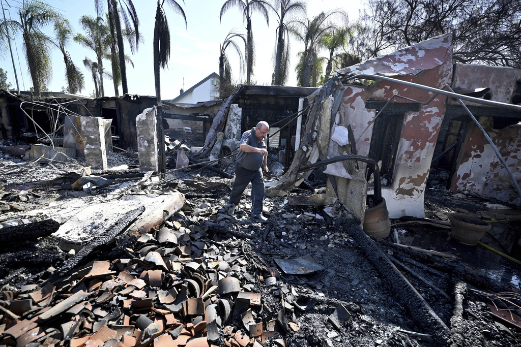 Home owner Andres Psaras walks through the burned rubble of the Spanish style home he purchased for his daughter and husband late last year following the Hawarden fire in the Alessandro Heights area of Riverside, Calif.