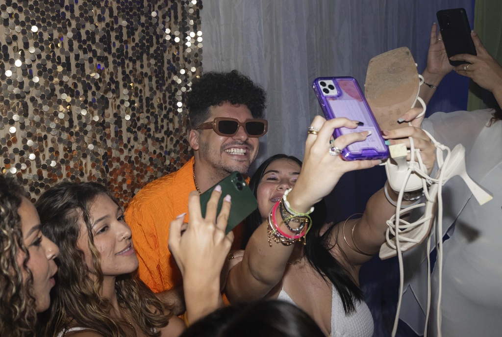 Dr. Pedro Juan Vázquez, better known by his stage name PJ Sin Suela, poses for group selfies at a high school prom in Camuy, Puerto Rico