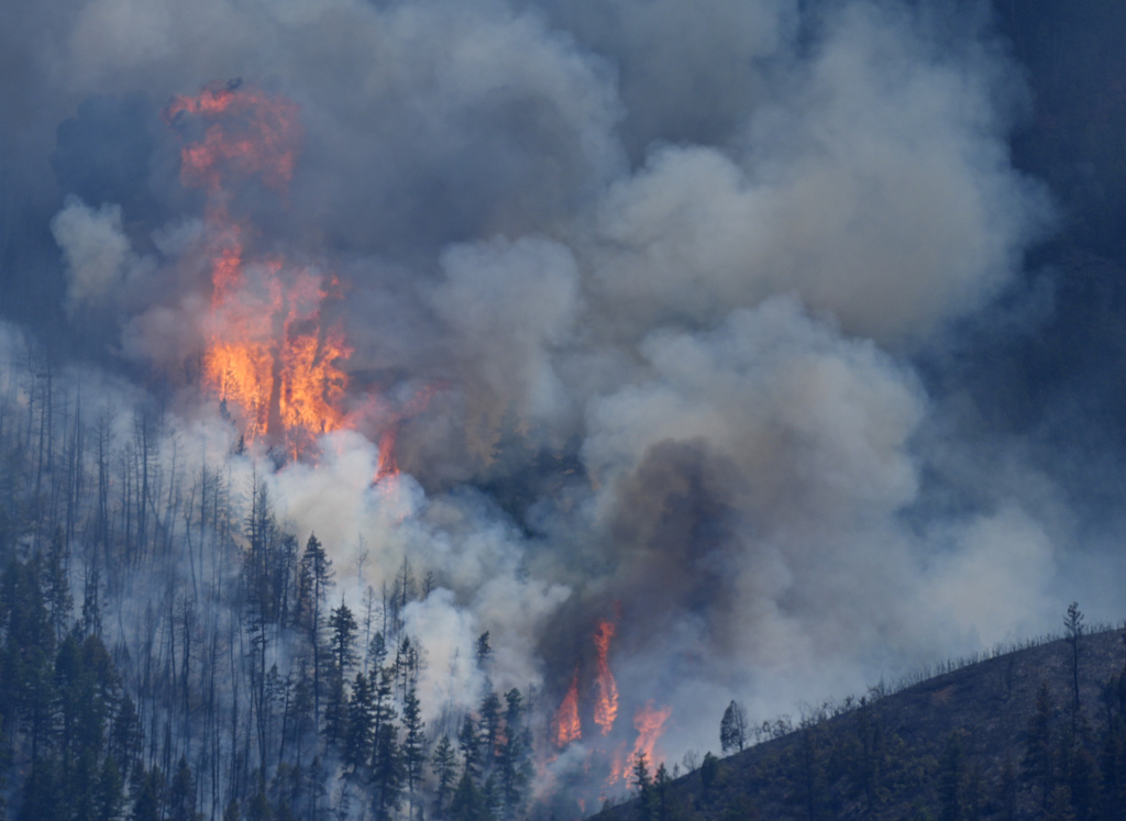 Flames rise amid billowing clouds of smoke as a wildland fire burns over ridges near the Ken Caryl Ranch development southwest of Littleton, Colo. 