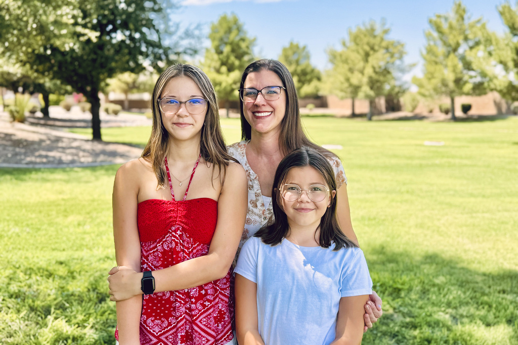 Audrey Jost stands with her daughters, Ellora, left, and Robyn, near their home in Gilbert, Ariz.
