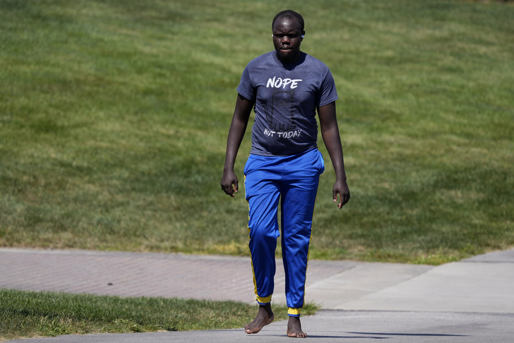 Ronald Okee, of Des Moines, Iowa, walks barefoot along the asphalt trail as the heat index tops 100 degrees at Gray