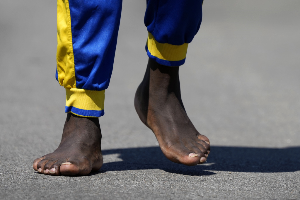 Ronald Okee, of Des Moines, Iowa, walks barefoot along the asphalt trail