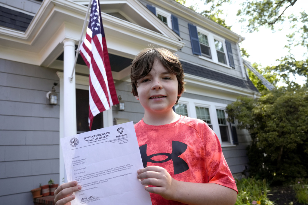 Danny Doherty, 12, of Norwood, Mass., stands for a photograph Wednesday, Aug. 21, 2024, in front of his home in Norwood, while holding a letter from the Town of Norwood Board of Health advising his family that they may not sell homemade ice cream at an ice cream stand near their home.