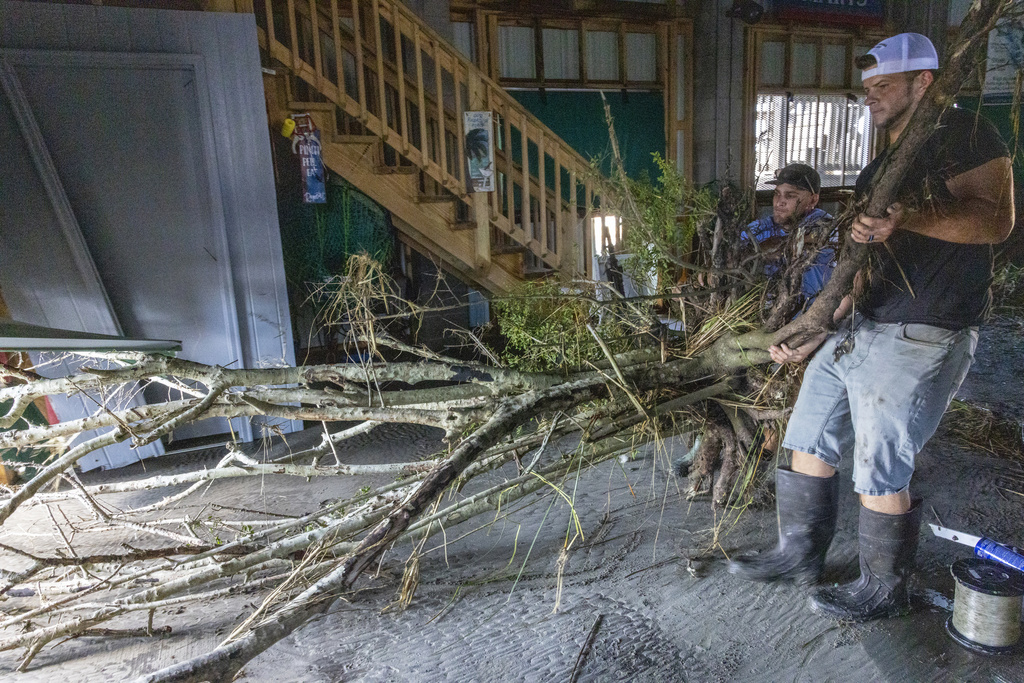 Jansen Pellegrin, back right, and Drew Foret, right, remove a small tree that floated into a living room area at their fishing camp from Hurricane Francine in Terrebonne Parish, La., Thursday, Sept. 12, 2024.