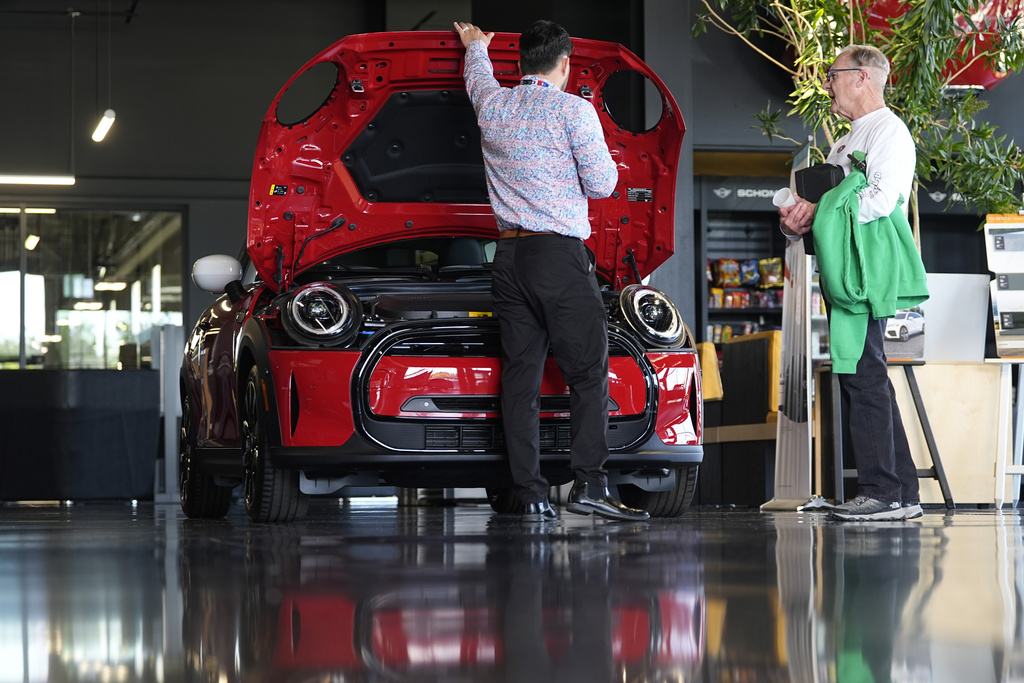 A salesperson shows an unsold 2024 Cooper SE electric hardtop to a prospective buyer in the showroom of a Mini dealership in Highlands Ranch, Colo.