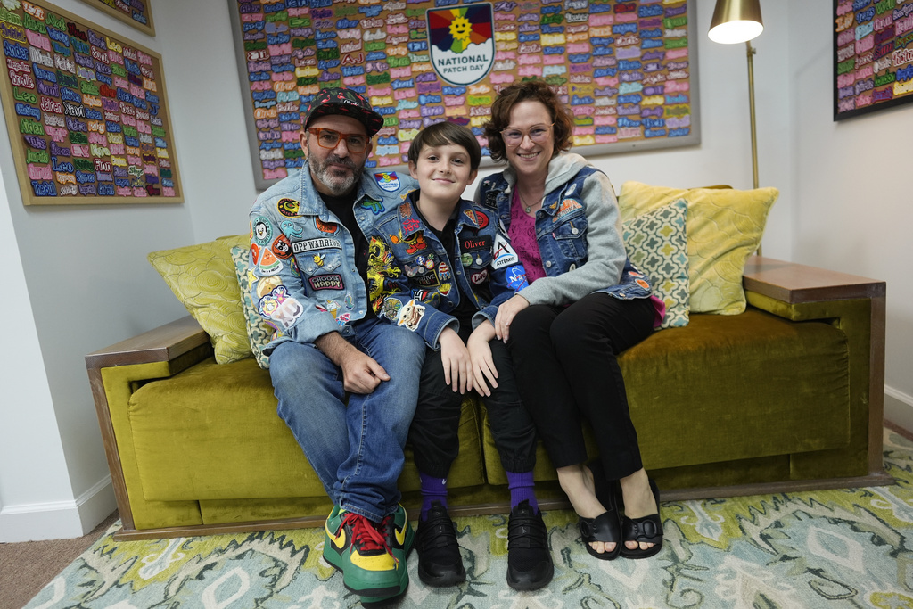 Brian Burkhardt, left, and Trisha Brookbank, right, pose for a picture with their son Oliver Burkhardt, 13, in the offices of the Oliver Patch Project