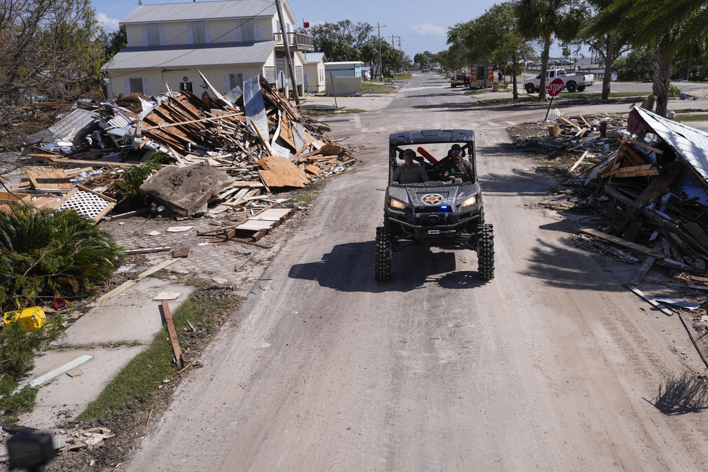 Law enforcement officers from the Florida Fish Wildlife and Conservation Commission drive past destruction in the aftermath of Hurricane Helene, in Cedar Key, Fla.