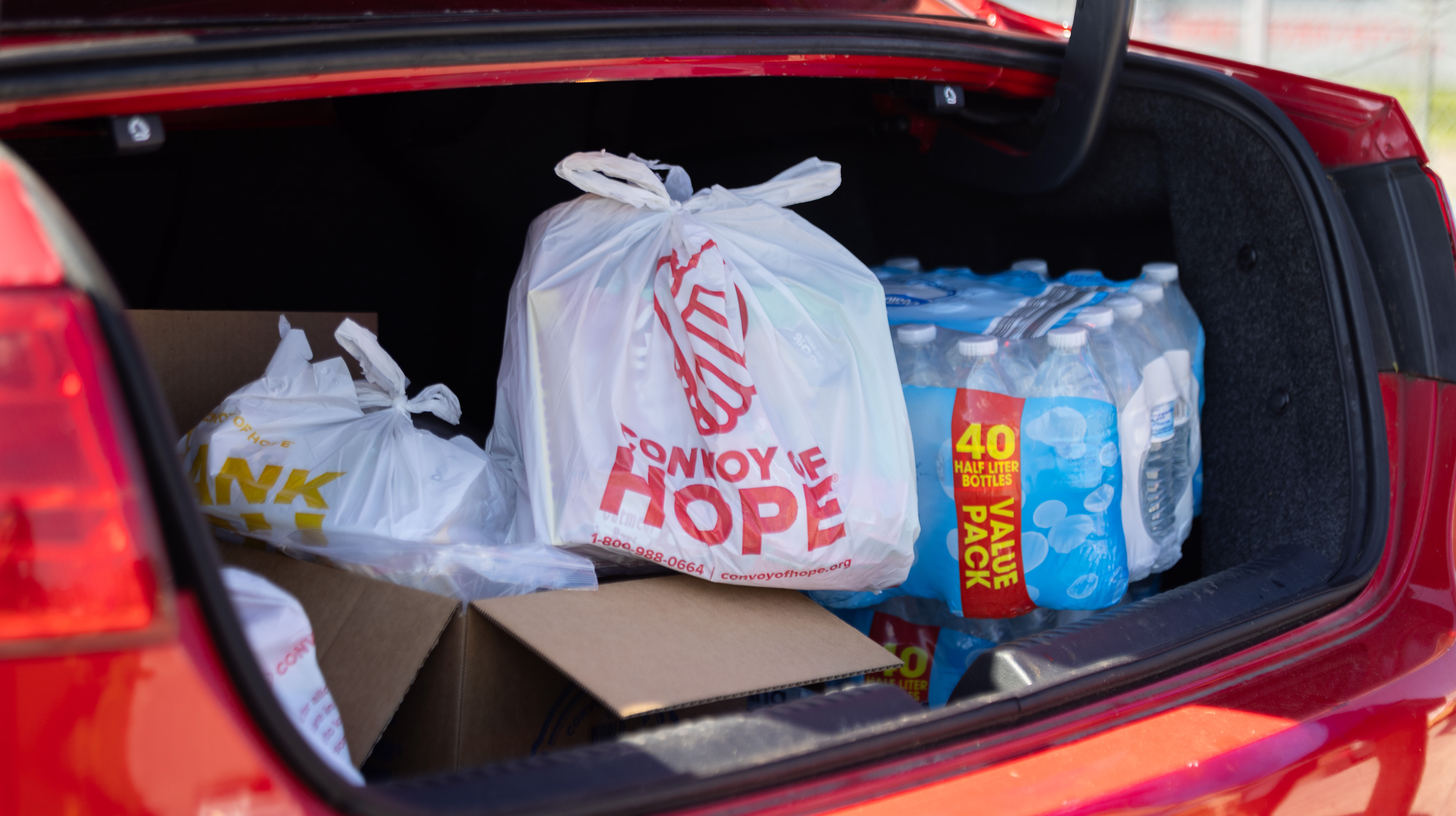 Open trunk with a bag of groceries and a case of water