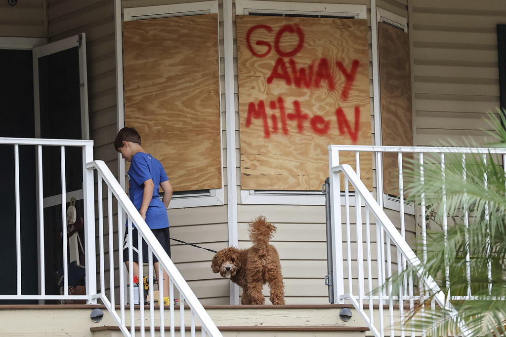 Noah Weibel and his dog Cookie climb the steps to their home as their family prepares for Hurricane Milton in Port Richey, Fla.