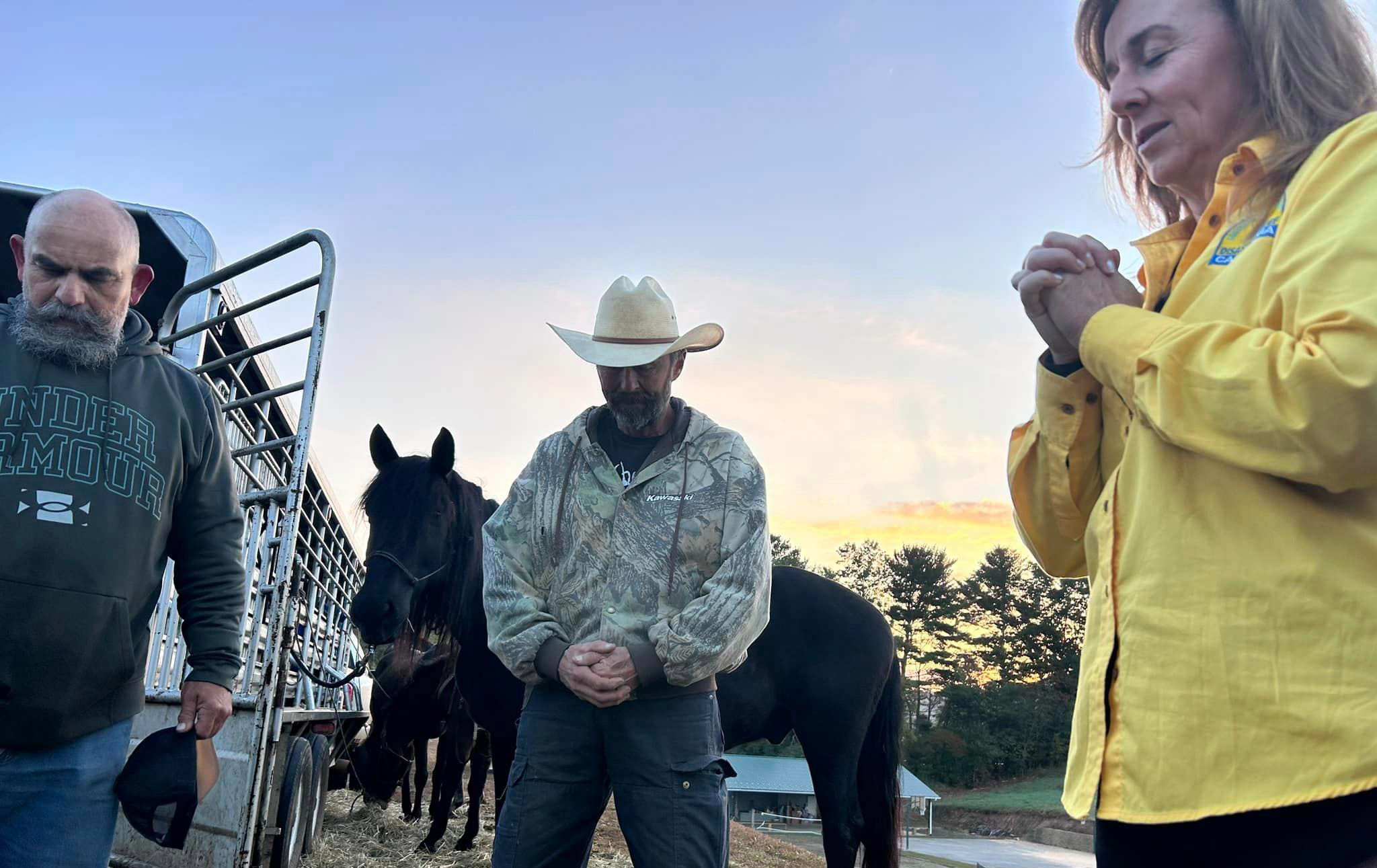 Two men and a woman, praying. Mule in the background