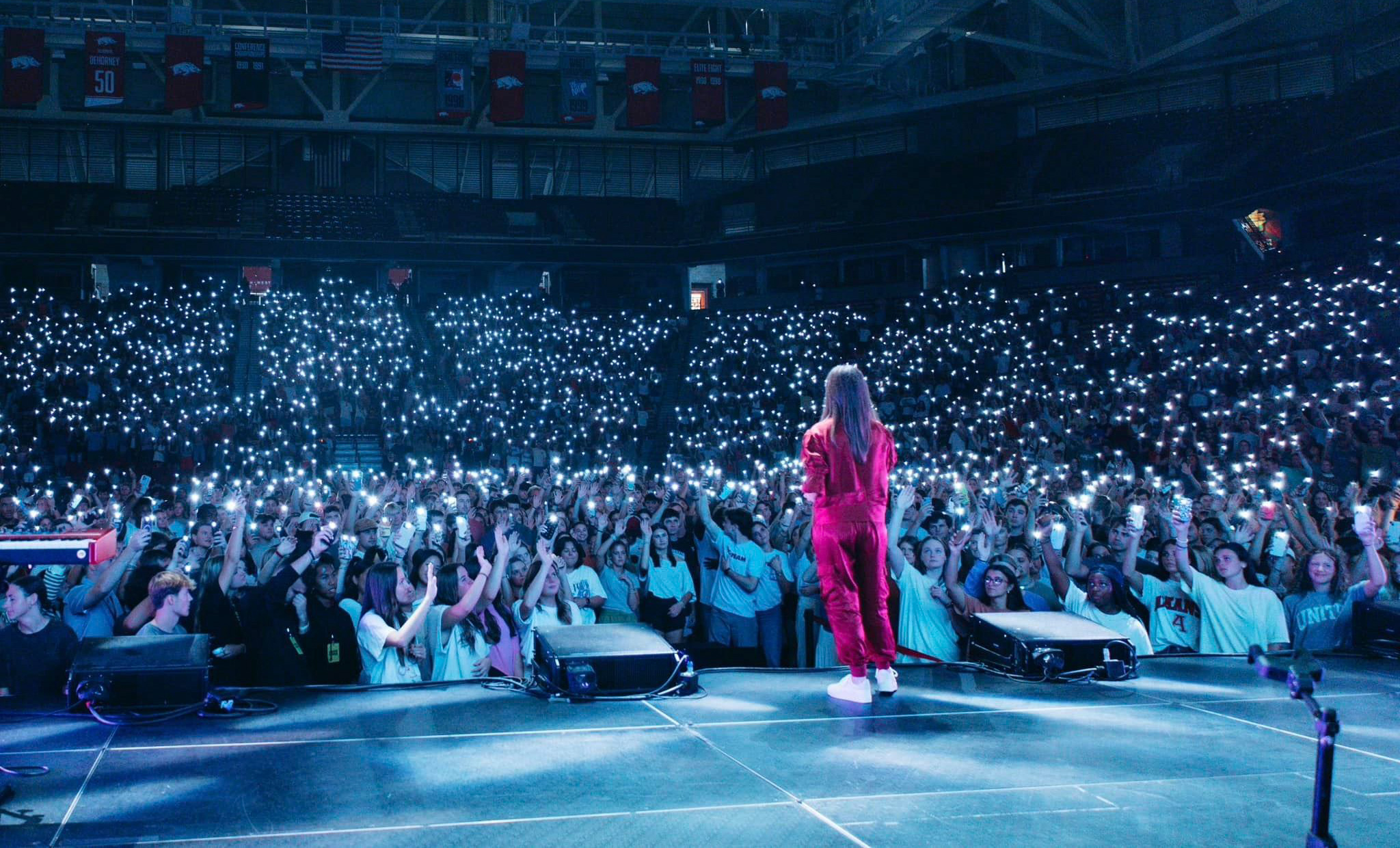 Woman in red in front of huge college campus crowd in stadium