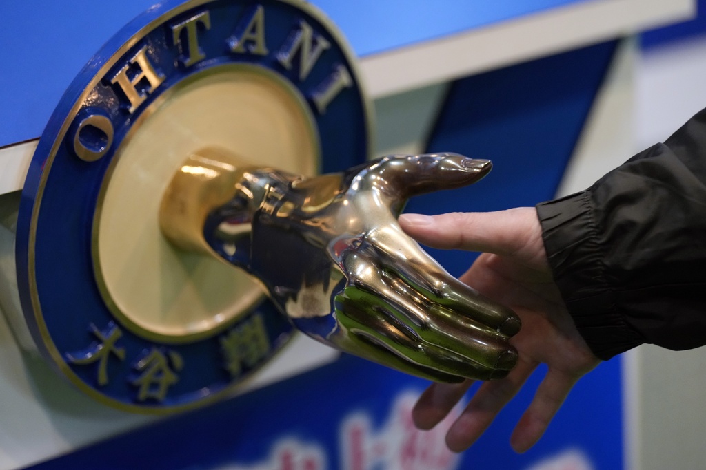 A visitor shakes hands with an iron model of Shohei Ohtani of the Los Angeles Dodgers, displayed at a local municipal government building in Oshu, northeastern Japan, the hometown of Ohtani, Tuesday, Oct. 29, 2024.