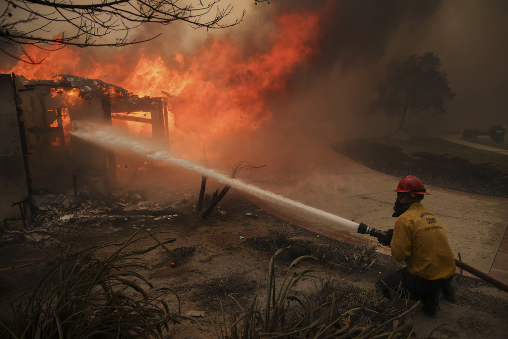 Firefighters spray water on a burning structure during the Mountain Fire near Camarillo, Calif. 