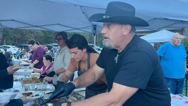 Man in cowboy hat feeding people