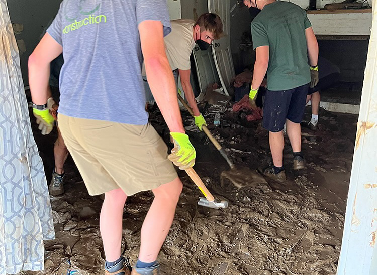 Volunteers with shovels cleaning mud from a home