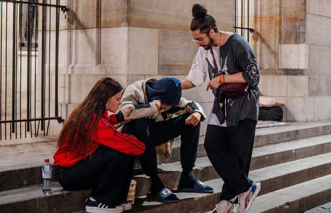 Two people praying for a young man on the steps