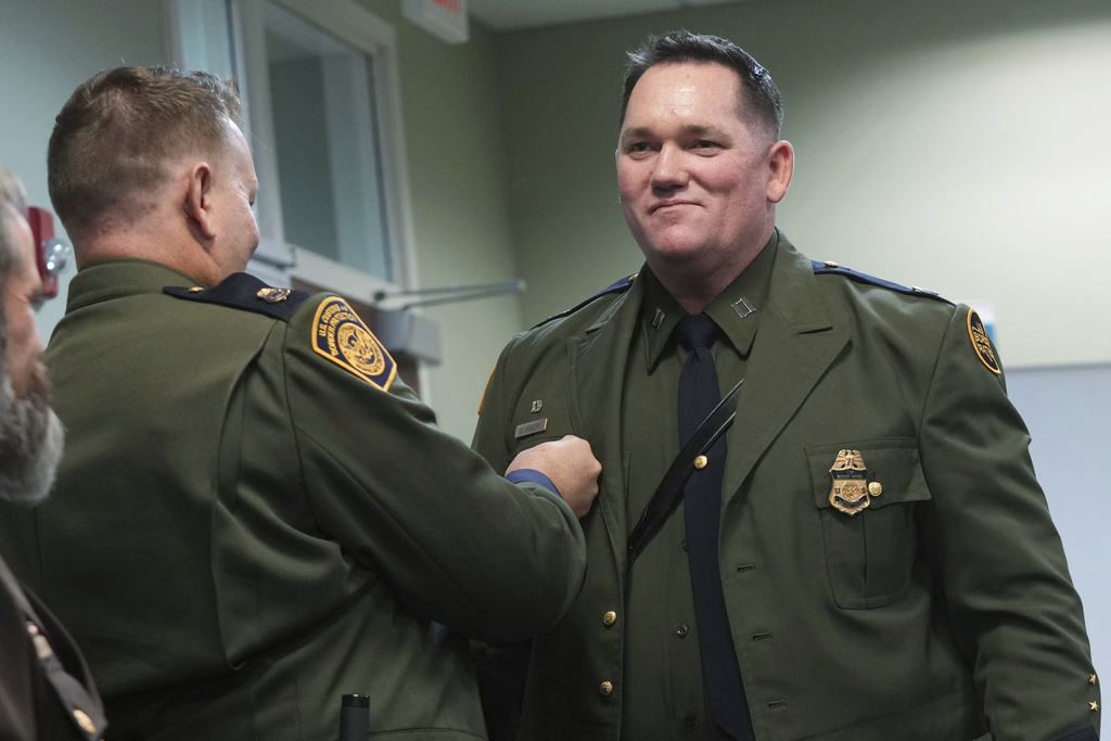 order Patrol Agent Matthew A. Kiniery smiles as Chaplaincy program manager Spencer Hatch pins the chaplain pin on his uniform