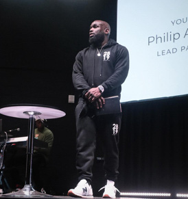 Man on stage with small table in front of him