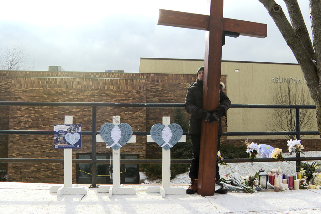 Dan Beazley stands with the homemade cross he brought from Michigan for victims of a shooting at Abundant Life Christian School 