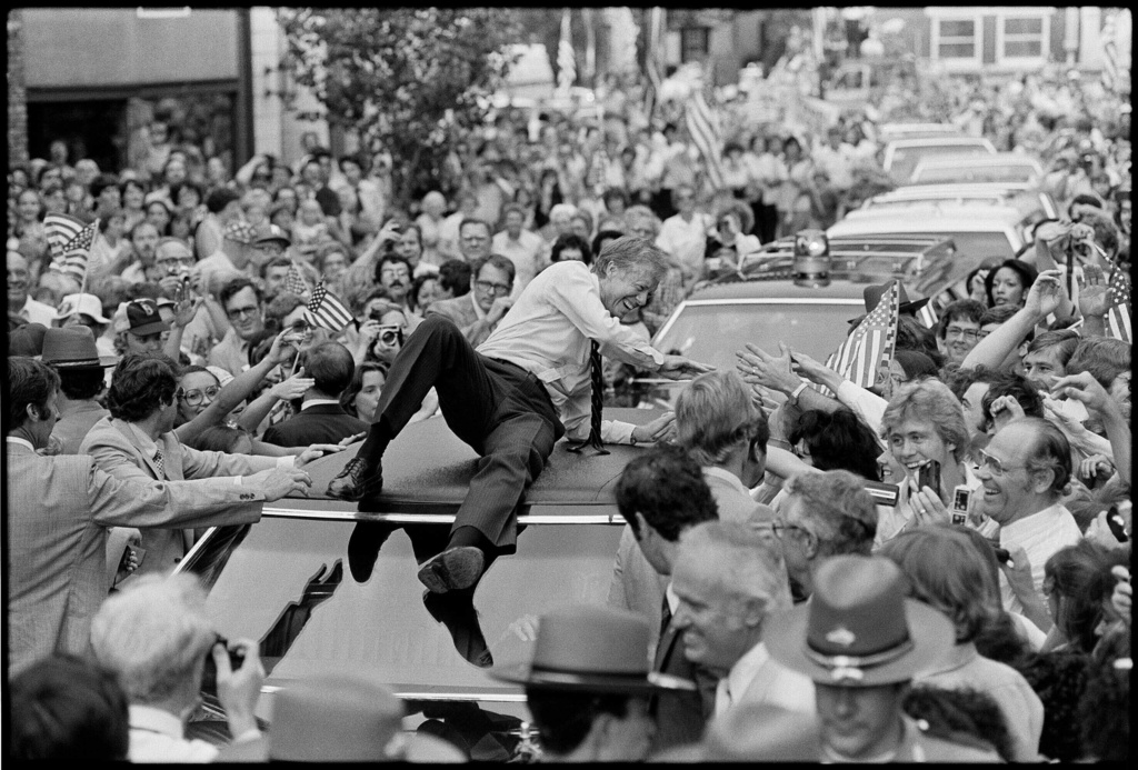 President Jimmy Carter leans across the roof of his car to shake hands along the parade route through Bardstown, Ky., July 31, 1979