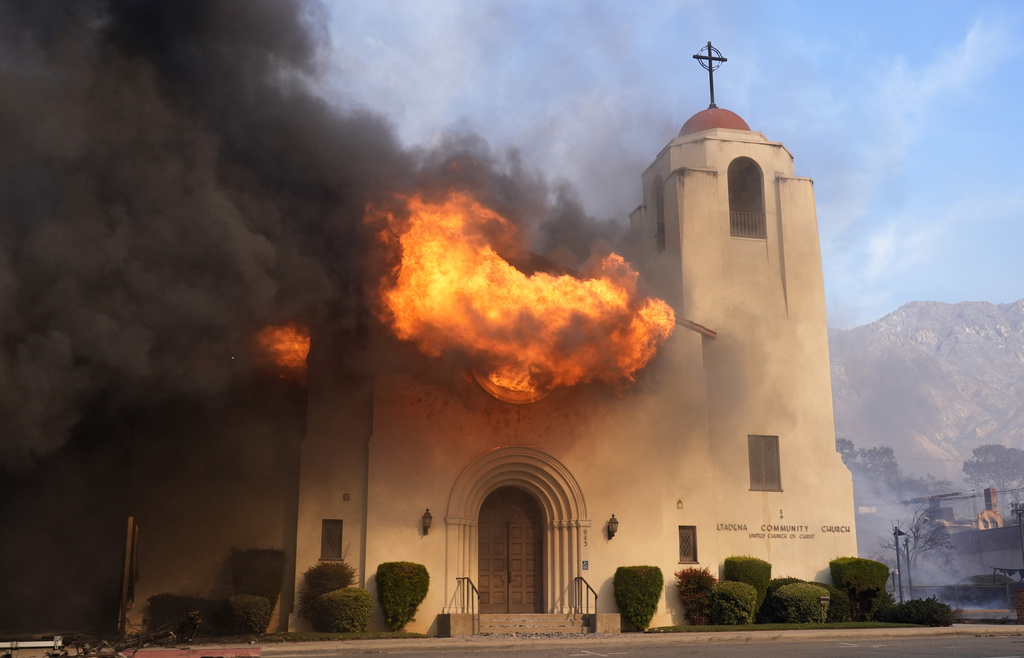 Fire explodes out of a window of the Altadena Community Church in the downtown Altadena section of Pasadena