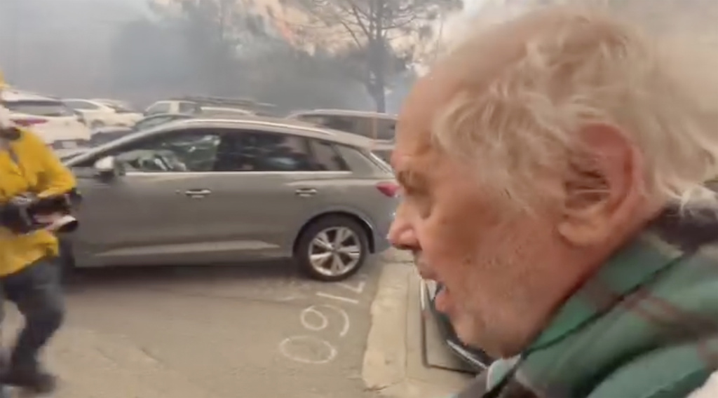 This image taken from video provided by Aaron Samson shows his 83-year-old father-in-law escaping the wildfires after they evacuated a vehicle near Pacific Palisades, Calif.