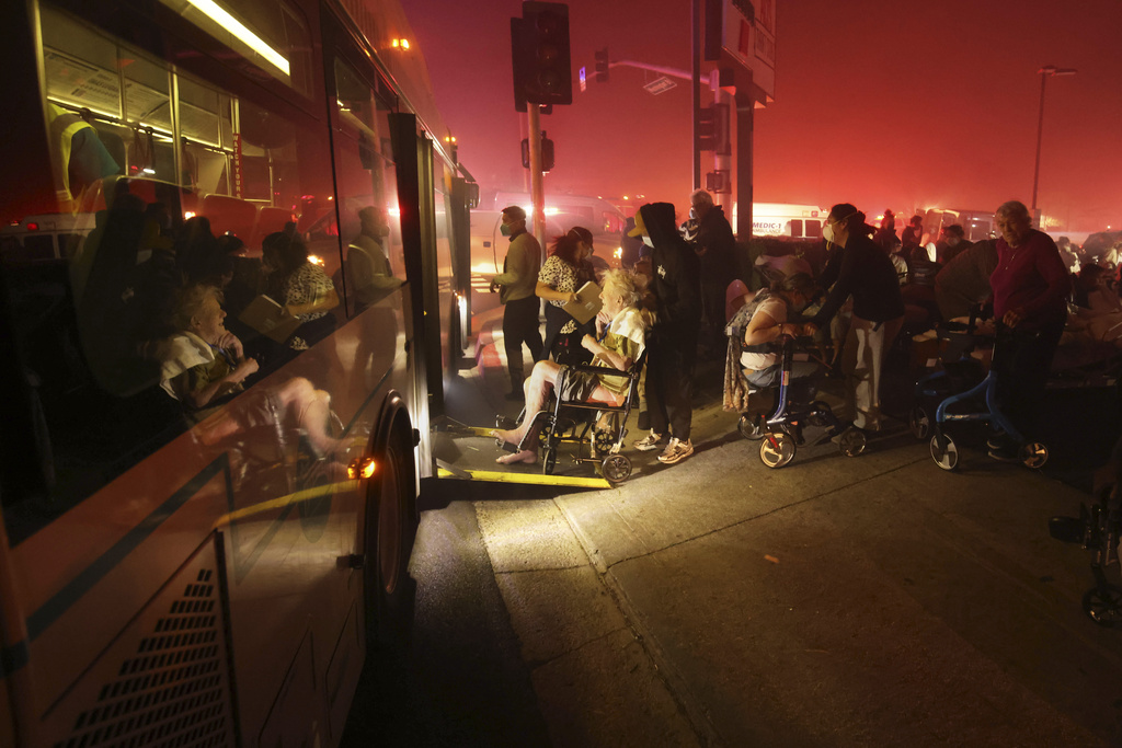 Residents of a senior center are evacuated and loaded into a bus as the Eaton Fire approaches