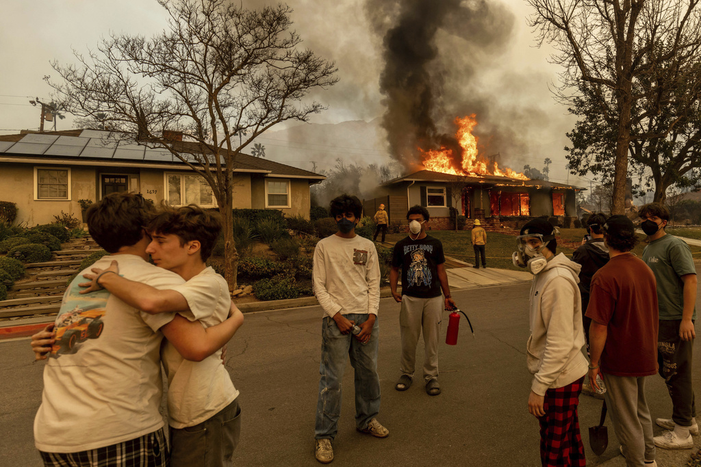 Residents embrace outside of a burning property as the Eaton Fire swept through Altadena, Calif.