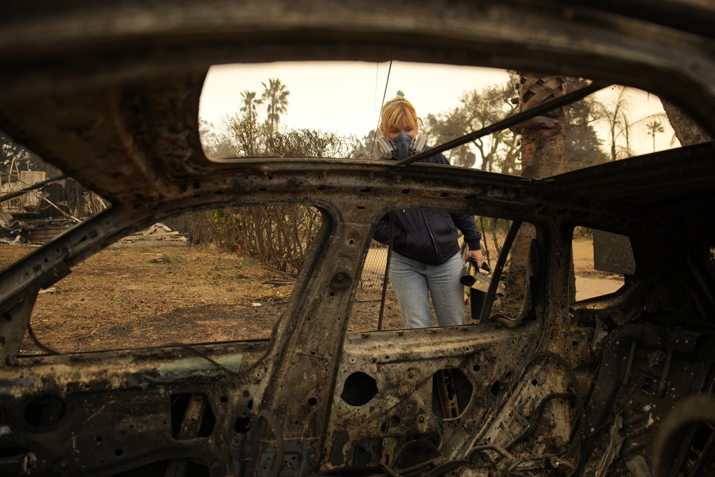 Lisa Renn looks at remains of car in Altadena, Calif.