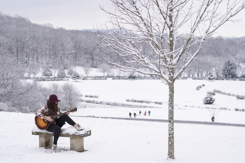 Victoria Collings plays her guitar on a snow covered bench in Nashville, Tenn.