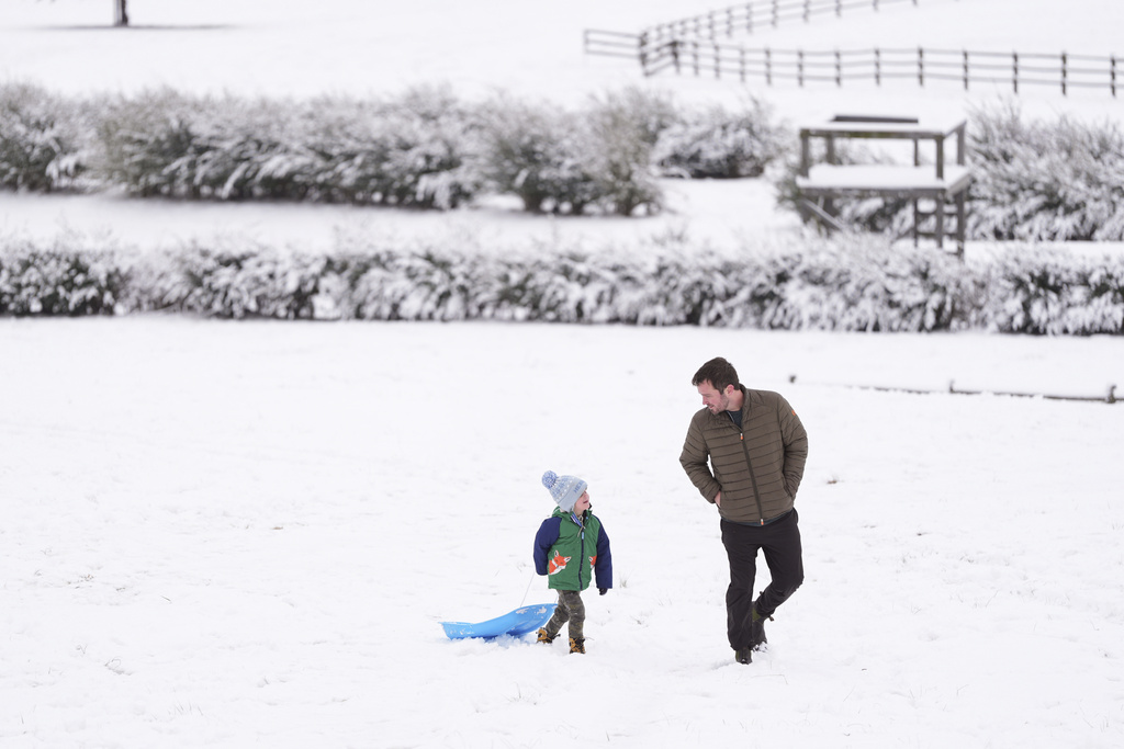 Henry Miller, left, walks up a snow covered hill with his father Nate in Nashville, Tenn.