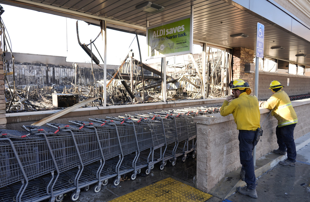 Clean-up workers look inside the interior of Aldi Food Market after it was destroyed by the Eaton Fire