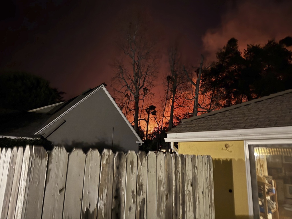 The Eaton wildfire approaches the yellow home of the Prata family in Altadena, California