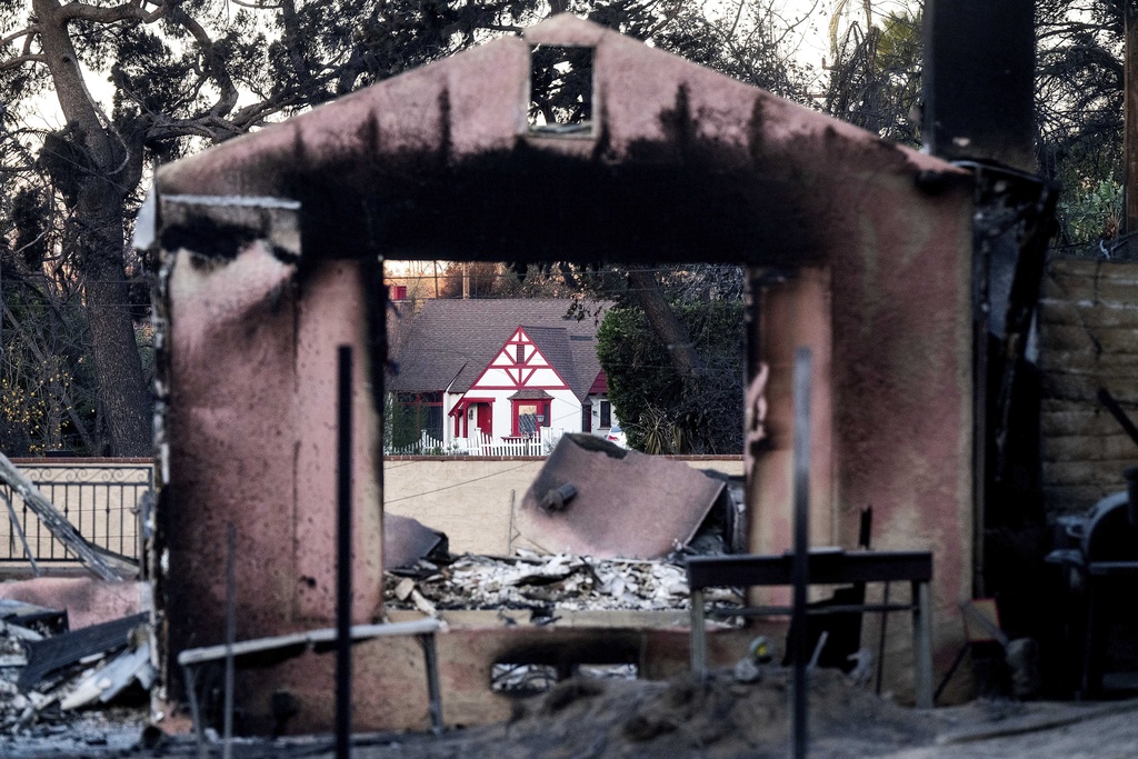 A home destroyed by the Eaton Fire stands in front of a home that survived in Altadena. Calif.