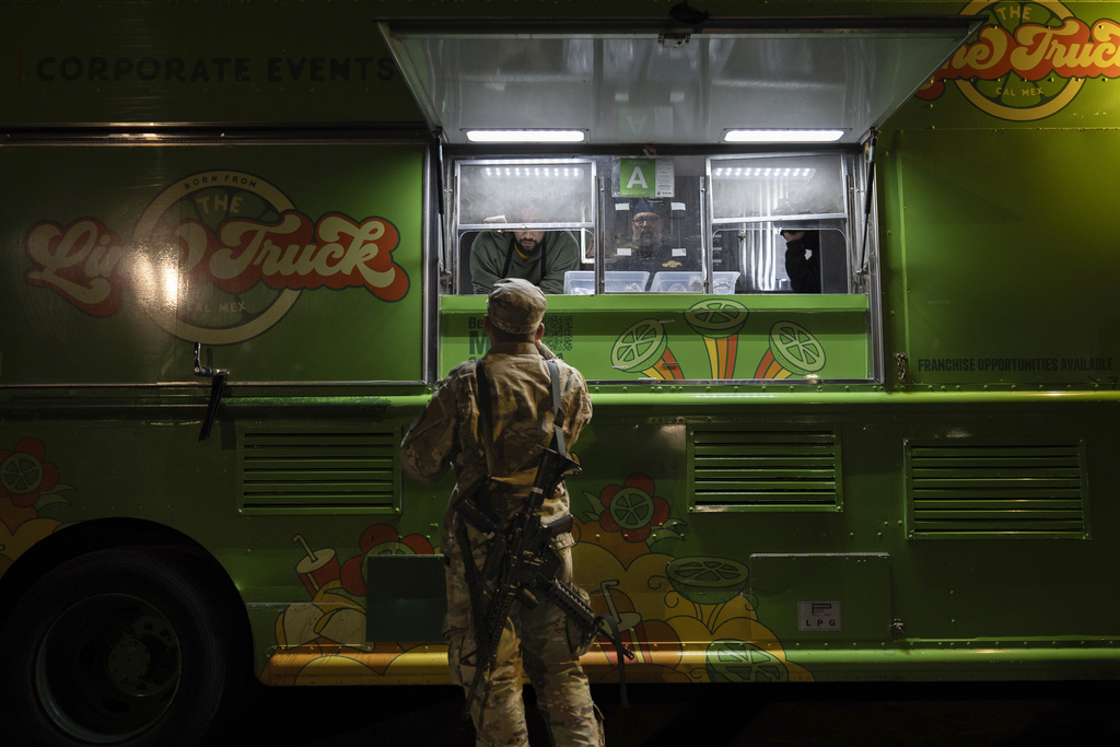 World Central Kitchen Chef Corp member Daniel Shemtob, upper left, and Benton Atkisson, right, serve a member of the California National Guard from his food truck, The Lime Truck