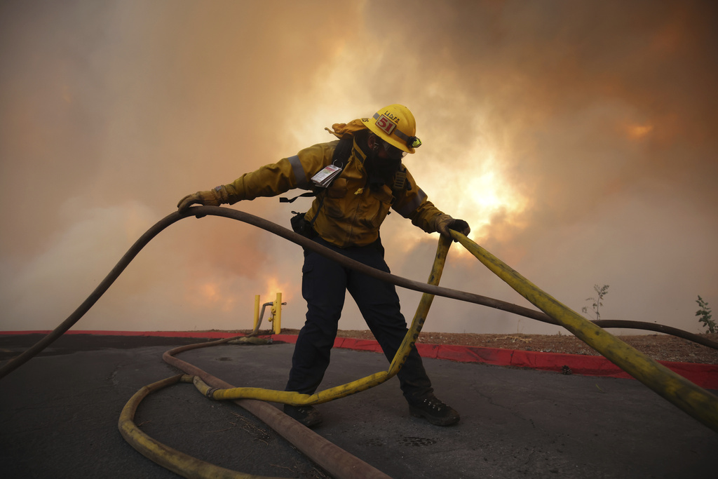 A firefighter sets out fire hoses to fight the Hughes Fire in Castaic, Calf.