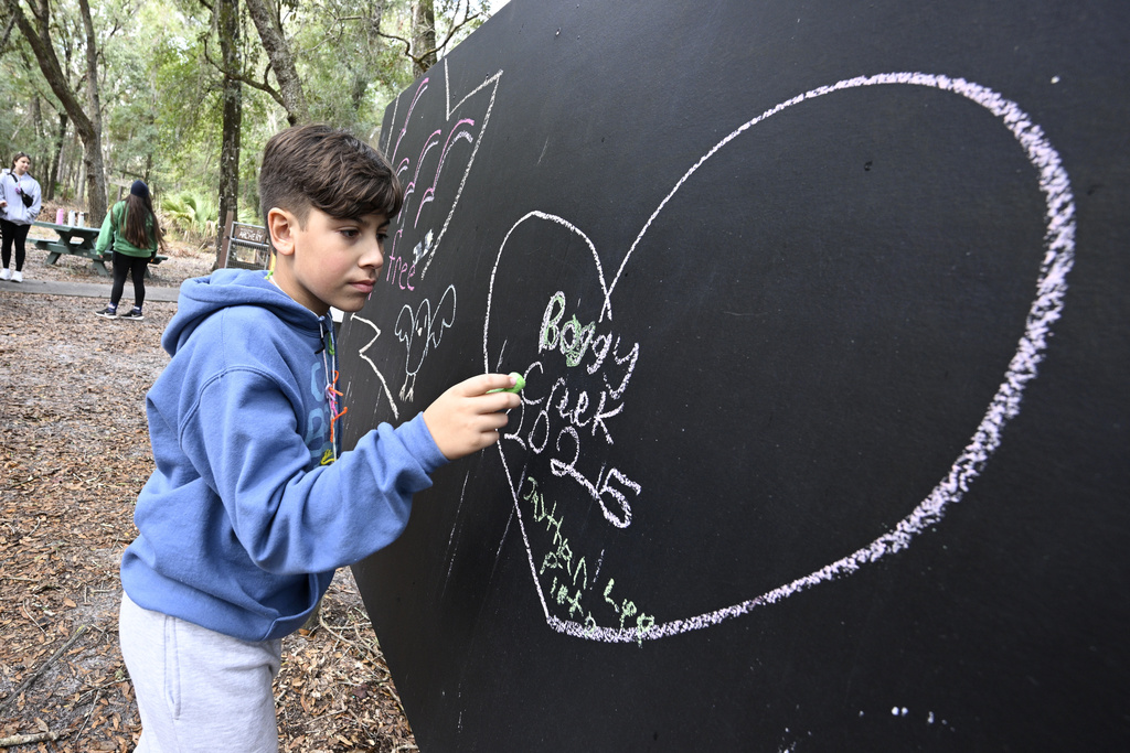 A child writes on a blackboard at Camp Boggy Creek, where children with serious illnesses and their families are provided with a free camp experience in Eustis, Fla. 