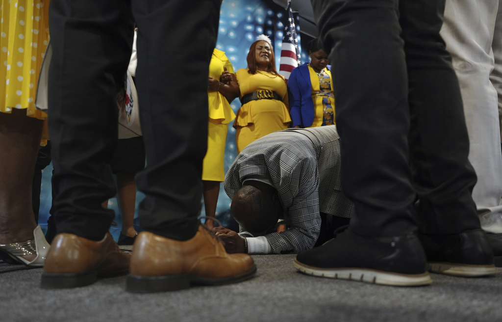 Rev. Reginald Silencieux kneels to pray, surrounded by the choir and worship team at the First Haitian Evangelical Church of Springfield