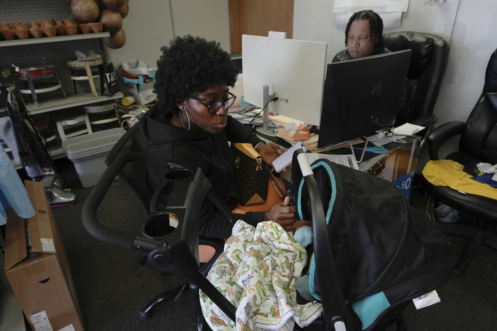 Dieutela Charles comforts her 6-month-old daughter while getting guidance on her U.S. residency from Haitian community leader Jacob Payton at his store in Springfield, Ohio