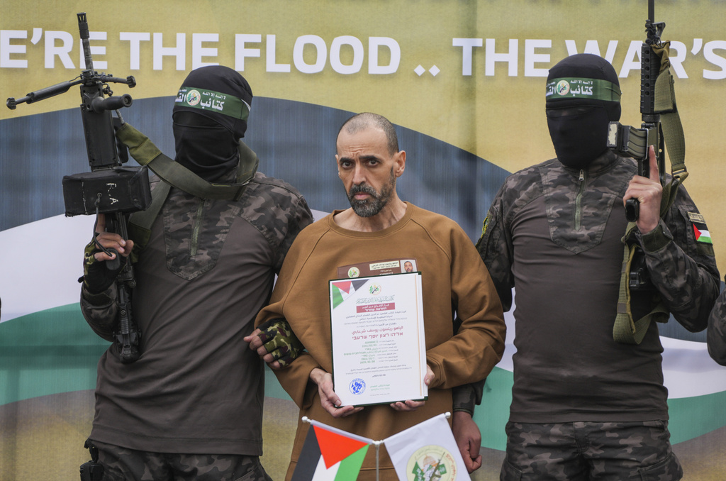 Israeli captive, Eli Sharabi, who has been held hostage by Hamas in Gaza since October 7, 2023, stands on a stage escorted by Hamas fighters before being handed over to the Red Cross