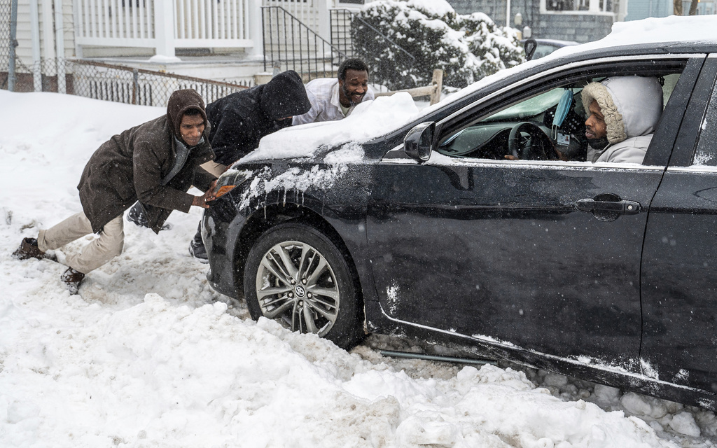 Ahmed Yasir steps on the gas while others push and rock his car was stuck in a driveway in Lewiston, Maine