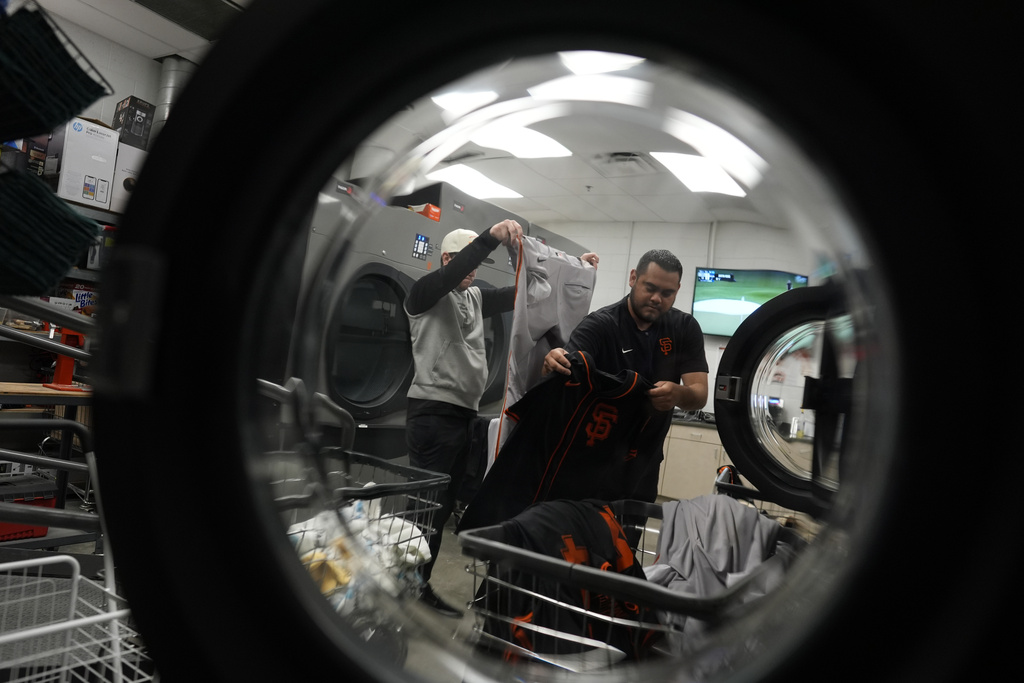 Arturo Maya, right, and Riley Halpin, left, inspect and sort laundry in the San Francisco Giants laundry room during spring training baseball practice at the team