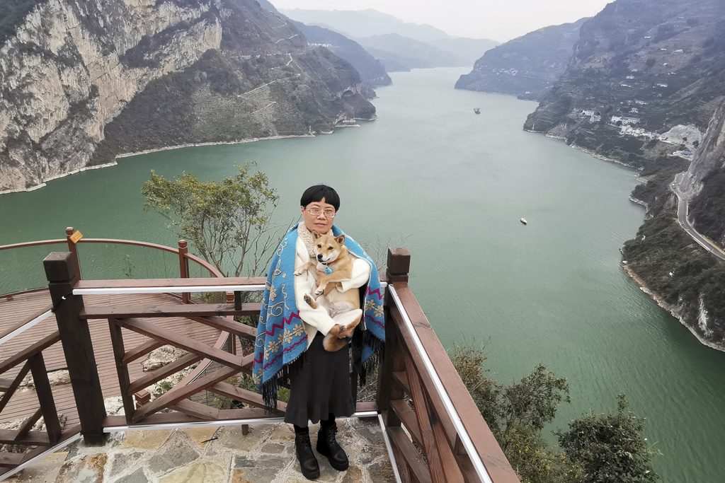 Zhang Yali with her dog "Little Cotton" near a mountain pass that went viral in China as "puppy mountain"