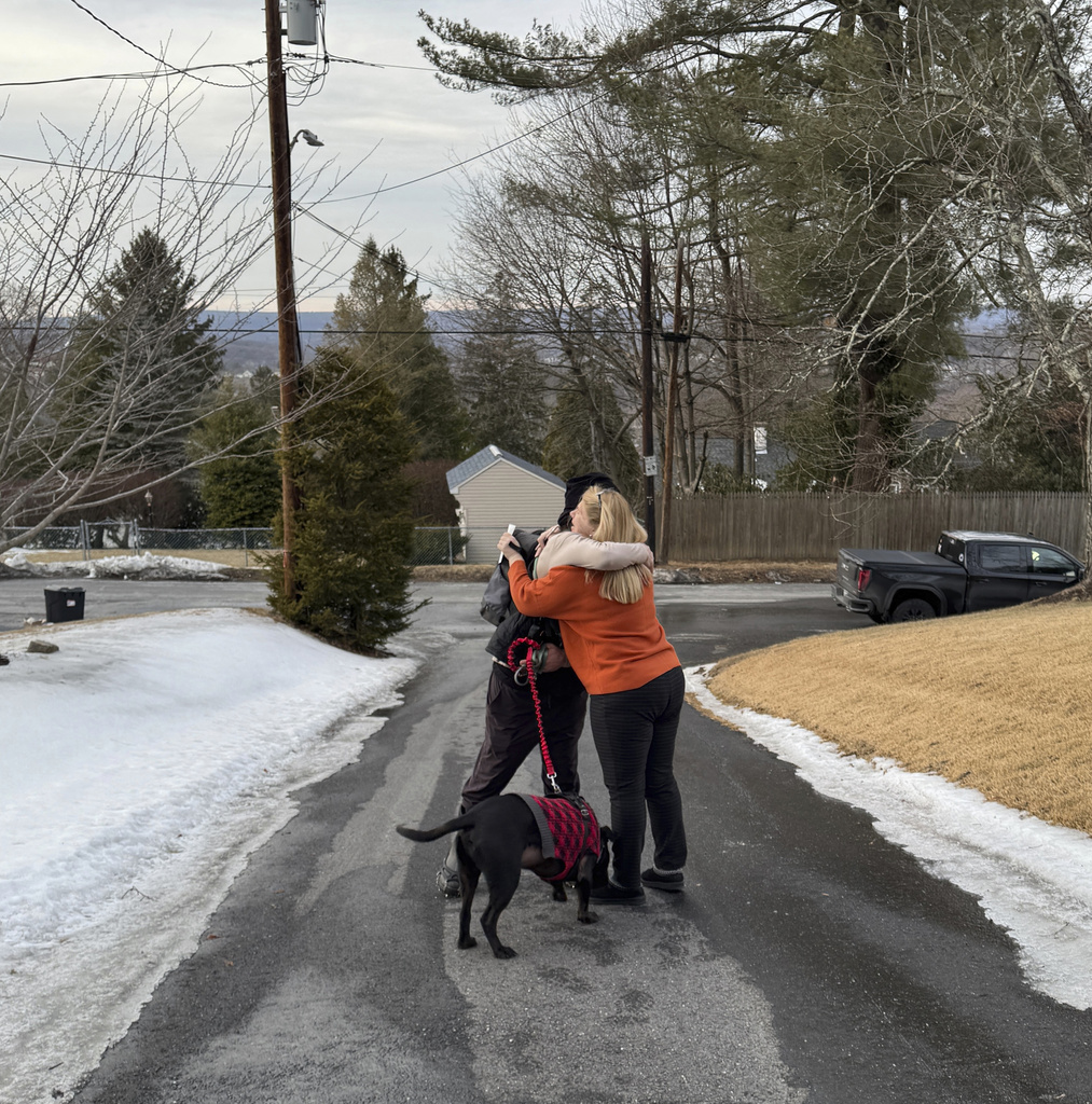 Pam Palko, right, embracing hiker Collin Leiby, with his dog Bass, after he found her missing six-month-old Golden retriever pup named Freddy,