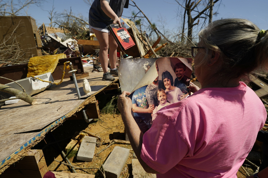 Patricia Blansett inspects a family portrait print, one of the few items that family and friends recovered intact, Sunday, March 16, 2025 from her relative