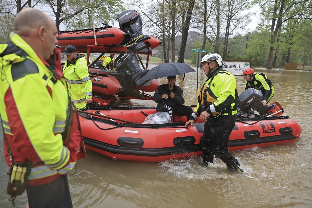 A resident is brought to dry land by boat after being rescued from flood waters by emergency responders from the Benton, Conway and Shannon Hills fire departments and the Pulaski County Emergency Management team in Shannon Hills, Ark.