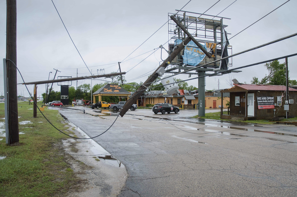 Broken power poles and power lines dangle across the parking lot of Quality Inn in Ada, Okla.