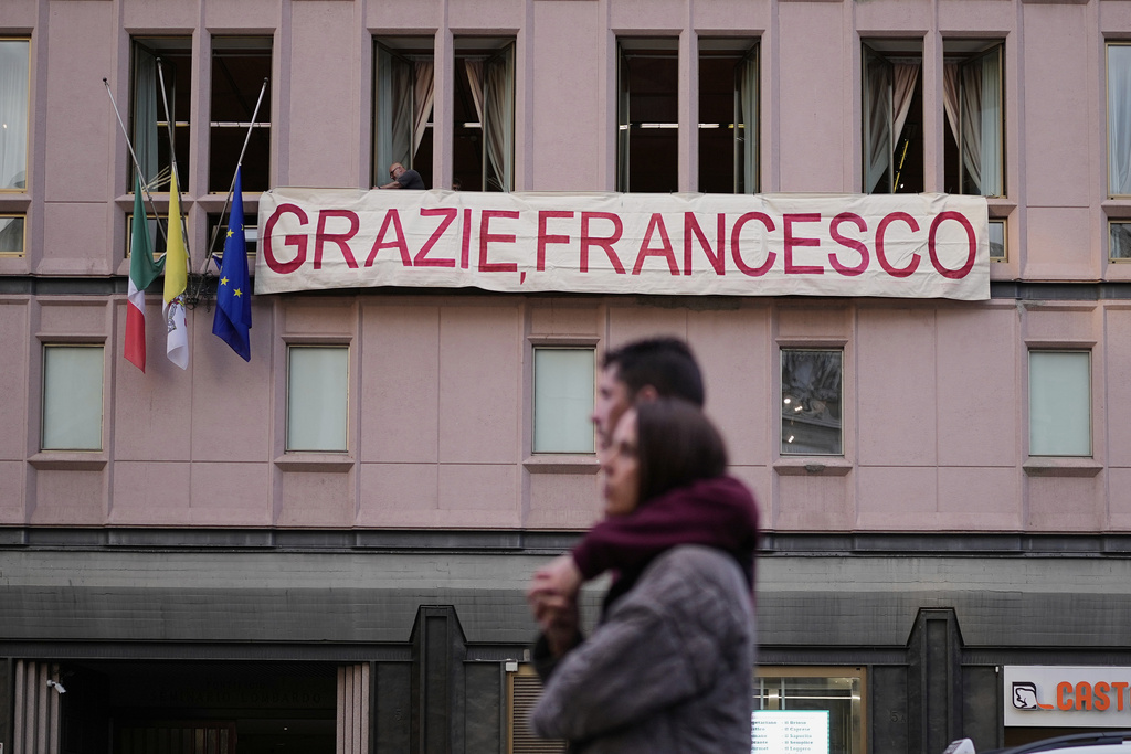 People set up a banner on a building near the Santa Maria Maggiore Basilica