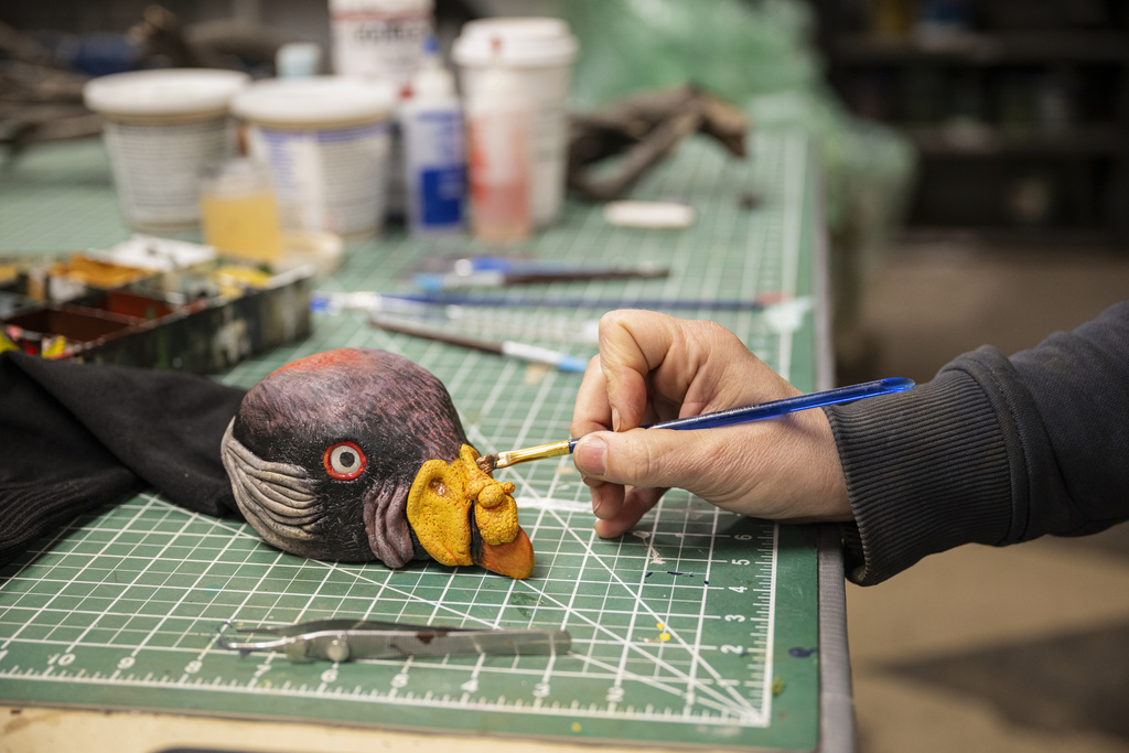 EGAD Manager Carolyn Fuchs paints details on a king vulture hand puppet