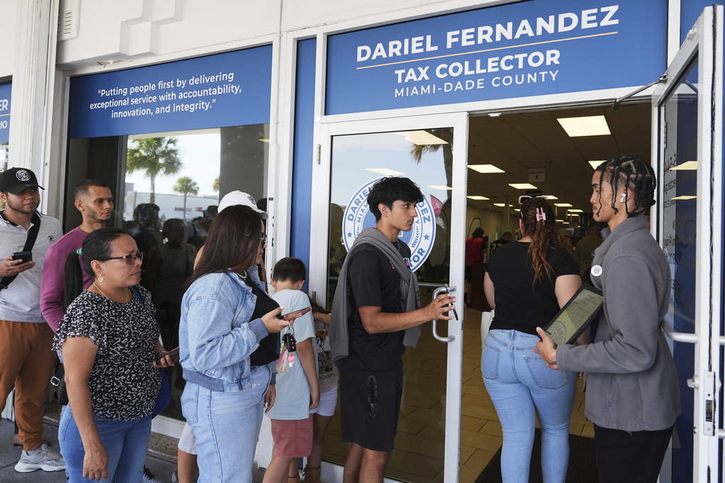 Customer Service representative Marlon Suarez, right, monitors the doorway outside of a Miami-Dade County Office of the Tax Collector